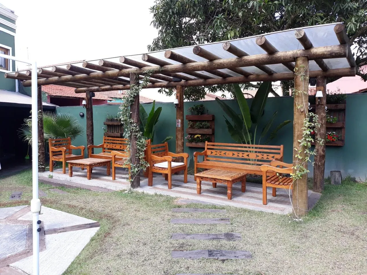 Pergolado de madeira com cobertura e móveis de jardim